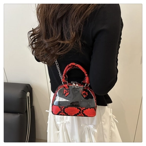 Detail view of red snakeskin textured shell bag with clear PVC on a female model