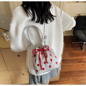 Close-up of silver bucket bag featuring red embroidered hearts and drawstring bow detail