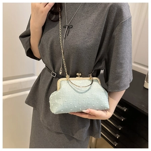 Detail of mint green jacquard clutch with gold kiss-lock and ring handle on model