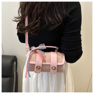 Détail du sac polochon rose tissé avec un nœud en ruban coloré et fermoirs dorés