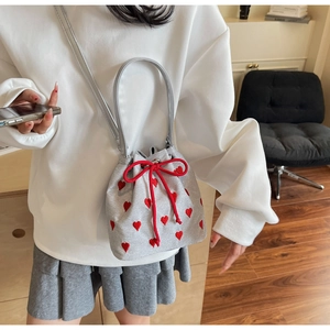Detail of silver bucket bag featuring red heart embroidery and drawstring closure