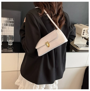 Close-up of white crocodile embossed baguette bag with elegant gold metal twist lock buckle