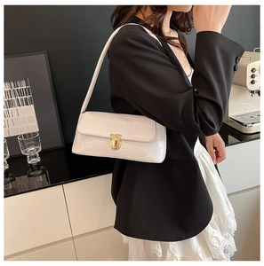 Close-up of white croc-effect underarm bag featuring a gold horseshoe metal twist lock