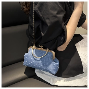 Close-up of blue polka dot denim shell bag with golden metal frame and chain strap