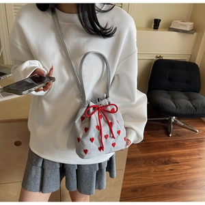 Silver bucket bag with red heart embroidery, drawstring closure, and crossbody strap