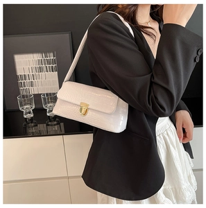 Detail of ivory crocodile pattern underarm bag featuring a metallic gold twist lock