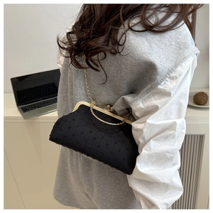 Detail of black vintage shell bag with gold clasp and elegant metal chain strap