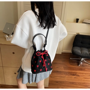 Detailed view of black quilted mini bucket bag with red heart embroidery and drawstring