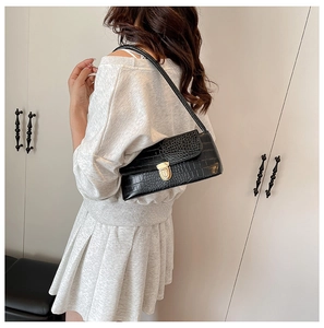 Detail view of the black crocodile pattern texture and gold buckle on underarm bag