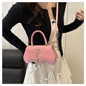 Close-up of pink woven crossbody bag with wavy edges and golden metal ornaments