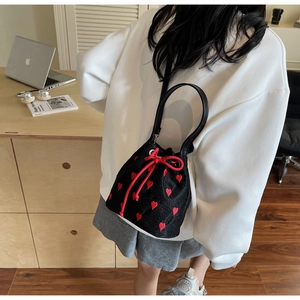 Detail of black drawstring bucket bag with red heart embroidery and rope closure