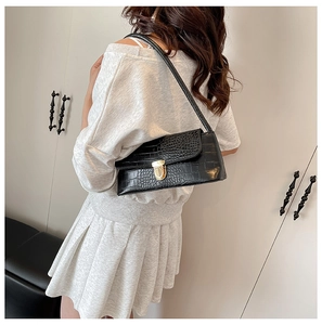 Detailed view of black crocodile pattern baguette bag with a premium gold buckle closure