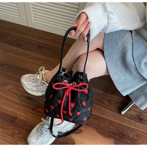 Close-up of black bucket bag with red heart sequins and thick rope drawstring bow