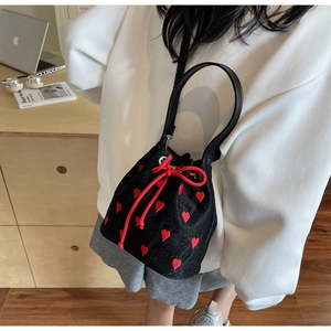 Detail shot of black bucket bag with red heart embroidery and drawstring closure