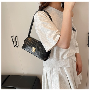 Detail of black crocodile texture underarm bag featuring a vintage golden twist lock closure