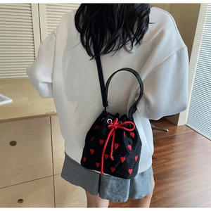 Back view of a model wearing a black bucket bag with red heart embroidery and drawstring