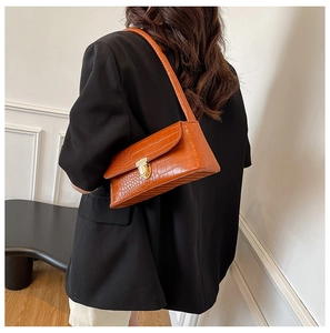 Detail of caramel crocodile embossed shoulder bag featuring a sleek golden metal buckle