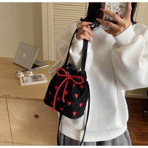 Detail of red heart embroidery on a black bucket bag with a stylish bow drawstring closure