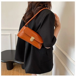 Detailed close-up of orange crocodile pattern shoulder bag with golden buckle on model