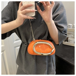 Gros plan du sac coquillage orange vif avec grand fermoir en C doré et chaîne métal