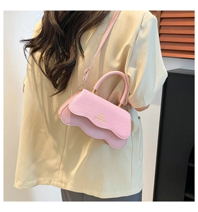 Detail of light pink crossbody bag with scalloped edges and gold JM logo on model