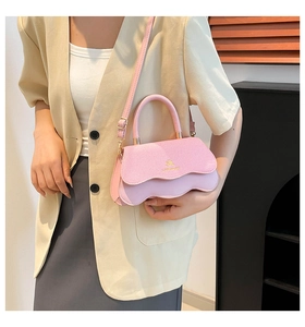 Detail of pink leather handbag with scalloped flap and gold logo on model's shoulder