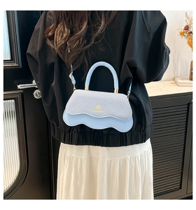 Detail of light blue crossbody bag featuring a wavy base and denim texture on model
