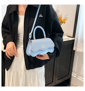 Detail of light blue crossbody bag with wavy flap and denim texture finish