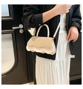 Detail of cream and straw crossbody bag with wavy edge design and gold logo