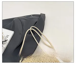 Detail of woven straw mini bag with soft cotton rope shoulder strap on a grey blazer