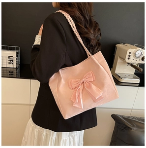 Detail of pink satin tote bag featuring a large bow and decorative woven shoulder strap