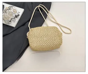 Detail showing handwoven texture of the beige mini straw bag with a smartphone for scale