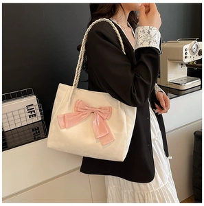 Detail of model wearing a minimalist tote bag featuring a large pink velvet bow detail