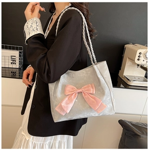 Detail of silver velvet tote bag featuring a pink satin bow and braided shoulder strap