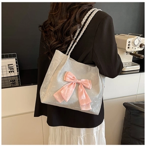 Close-up of gray tote bag with large pink bow and white woven rope handle on model