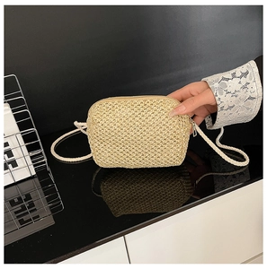 Detailed texture of hand-woven beige straw crossbody bag with metal zipper and thin strap