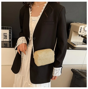 Close-up of beige woven crossbody camera bag with zipper and fine cord strap