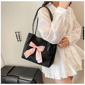 Detail of the woven shoulder strap and large pink satin bow on the black velvet tote bag