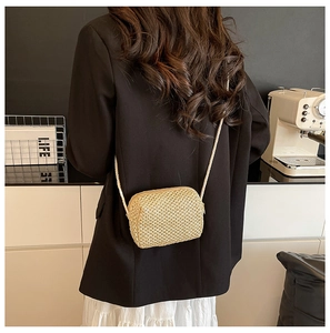 Detailed view of a handmade beige straw crossbody bag styled with a minimalist outfit