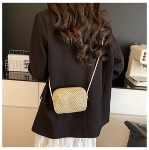 Detail of a mini hand-woven straw crossbody bag in beige with natural fiber texture
