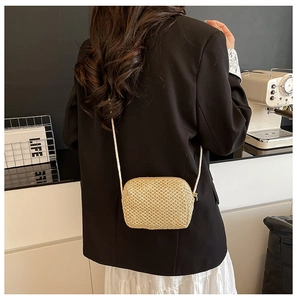 Mini hand-woven straw crossbody bag in cream gold shown worn in a lifestyle setting