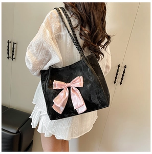 Detail of black velvet tote bag featuring a large pink satin bow and woven rope handles