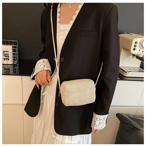 Detail of hand-woven beige straw crossbody bag featuring natural fiber texture and zipper