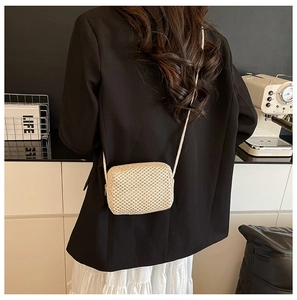 Detailed view of a mini handmade woven crossbody bag worn by a model for a summer look