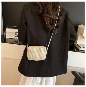 Detail of a beige handmade woven mini crossbody bag showing premium texture and strap