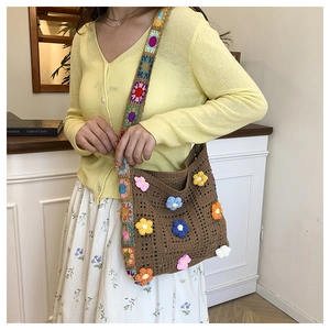 Close-up of bohemian crochet tote with colorful 3D floral accents and patterned strap