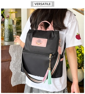 Detail view of black nylon backpack with pink trim and colorful tassel charm decoration