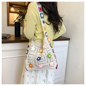 Detail of crochet tote bag featuring 3D floral ornaments and rainbow shoulder straps