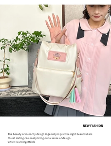 Detail of cream backpack with pink handles and colorful tassel charm decoration