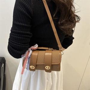 Brown woven cylindrical crossbody bag with gold buckles and a decorative plaid ribbon